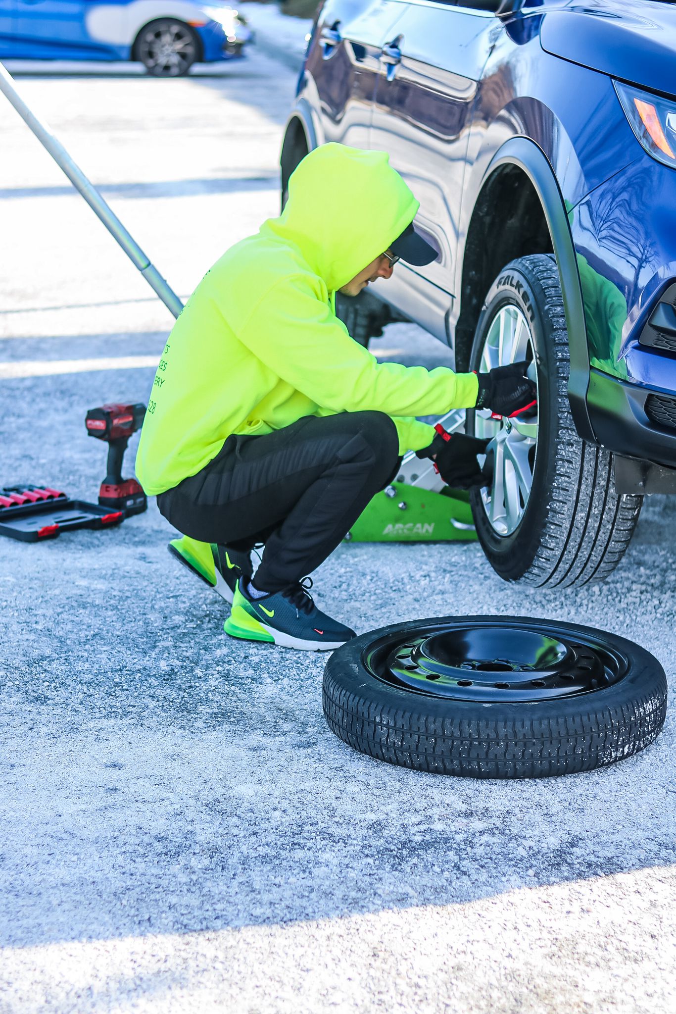 "Man performing a tire change on a vehicle as part of roadside assistance service"