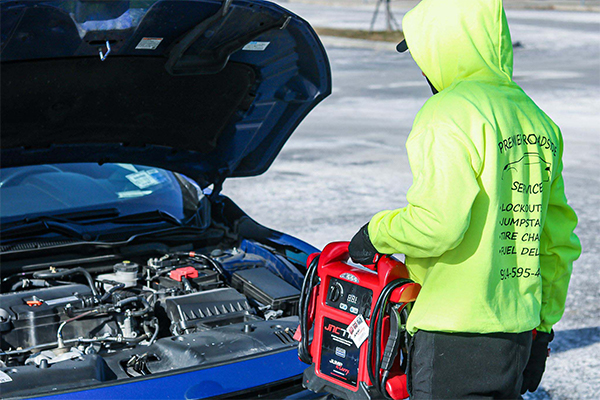 "Man providing jumpstart to a vehicle - Professional roadside assistance service for jump starting a car"